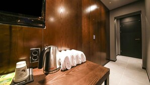 Une chambre d’hôtel avec un mur en bois, une machine à café, une bouilloire et des serviettes posées sur une table.