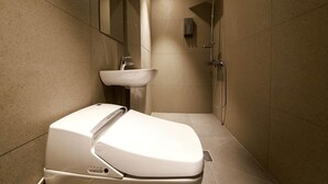 Une salle de bain moderne avec des toilettes, un lavabo et une douche, le tout de couleur blanche.