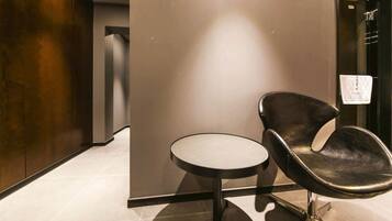 A modern interior with a round table and a single black leather chair.