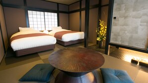 Habitación de hotel con dos camas, una mesa redonda y vistas al exterior.