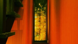 Un pasillo con paredes de madera y vistas a plantas de bambú a través de un vidrio.