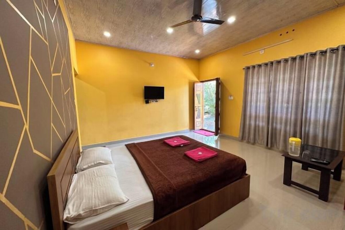 A bedroom with a bed, a desk, a chair, a television, and a window with curtains.