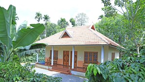 A traditional house with a tiled roof, surrounded by lush greenery and banana plants. - Himadri Retreat Cottages (Vythiri)