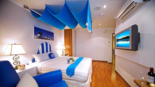 Una habitación de hotel con cama, televisión, suelo de madera y aire acondicionado instalado en la pared.