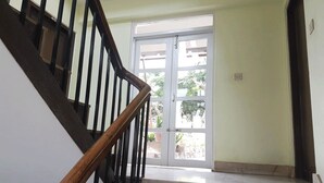 A staircase with a wooden handrail leading to a white door with glass panels. - Imperial Guest House (Kathmandu)