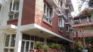 A multi-story building with a red brick facade, white balconies, and a gated entrance. - Imperial Guest House (Kathmandu)