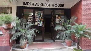The entrance of the Imperial Guest House with a sign above the door, potted plants, and a red brick wall. - Imperial Guest House (Kathmandu)