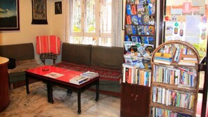 A living room with a sofa, a coffee table, a bookshelf, and a window with curtains. - Imperial Guest House (Kathmandu)