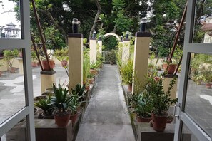 A pathway lined with potted plants leading to a traditional gate, surrounded by lush greenery. - Imperial Guest House (Kathmandu)