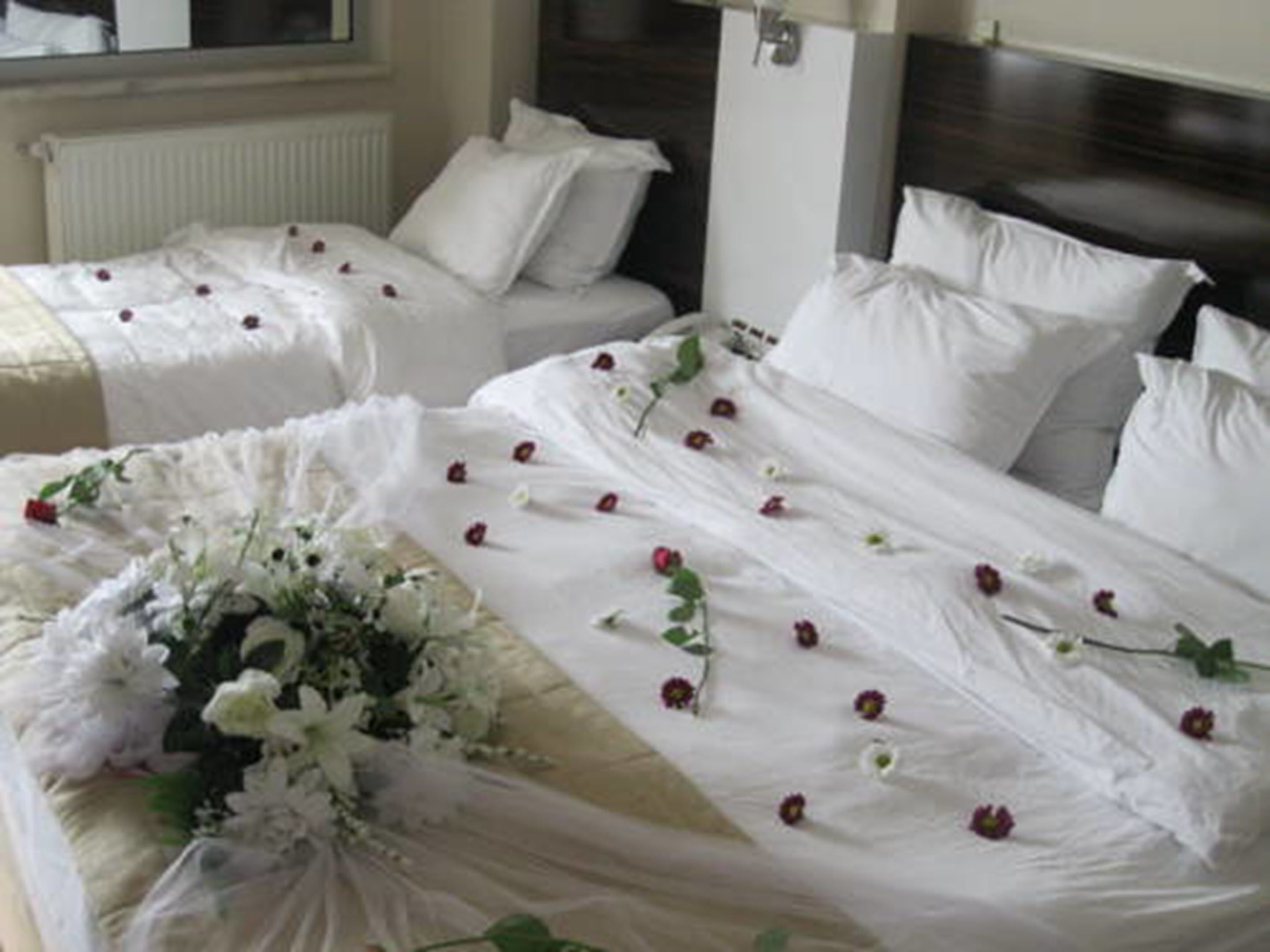 A hotel room with two beds, white bedding, and a floral arrangement on one bed.