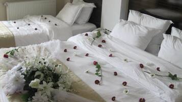 A hotel room with two beds, white bedding, and a floral arrangement on one bed.