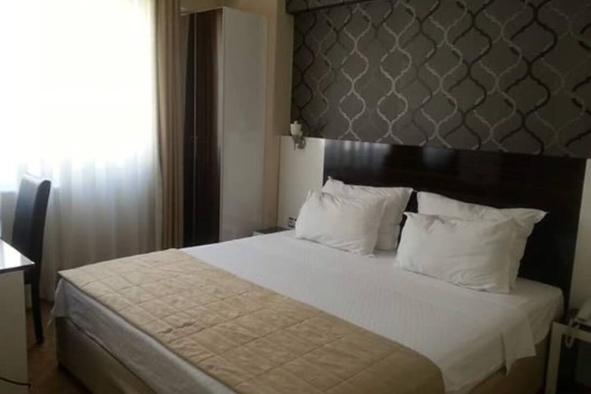 A hotel room with a bed, a desk, and a chair.