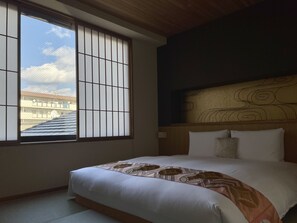 Una habitación de hotel con un ventanal grande, una cama con colcha estampada y un cabecero con diseño decorativo.