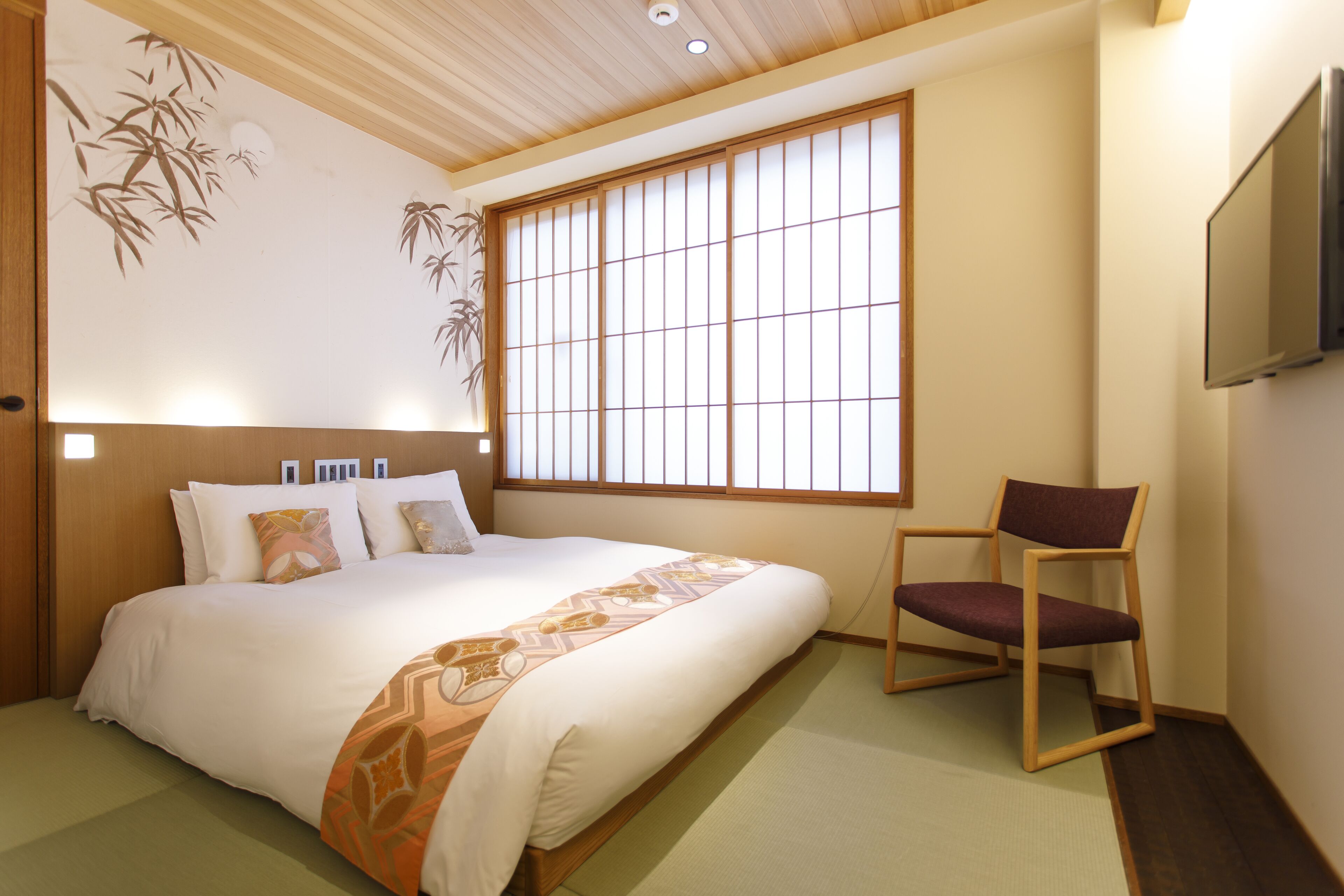 Une chambre à coucher bien aménagée, avec un grand lit, une chaise, un téléviseur et une fenêtre donnant sur un beau paysage.