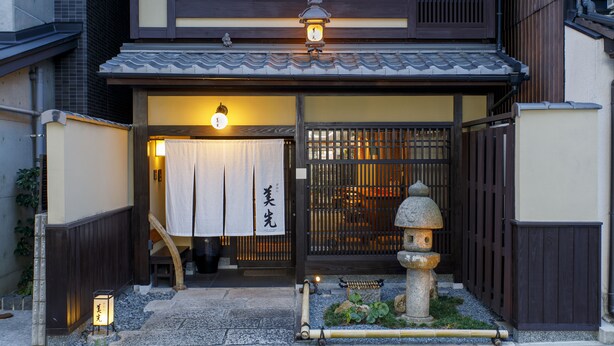 A traditional Japanese building with a tiled roof, wooden gates, and a stone lantern. - Gion Misen Furumonzen (Kyoto)