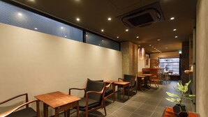 A restaurant with wooden tables and chairs, a tiled floor, and a plant on a wooden table. - Gion Misen Furumonzen (Kyoto)