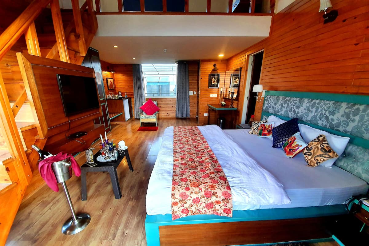 A spacious bedroom with a large bed, wooden walls, a television, and a small table with a tray.