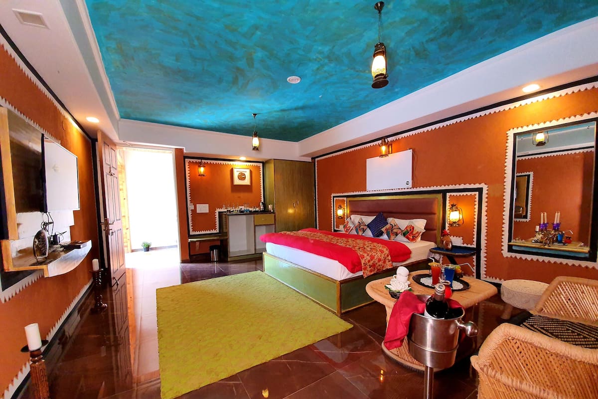A hotel room with a bed, a small desk, a chair, a mirror, and a window.