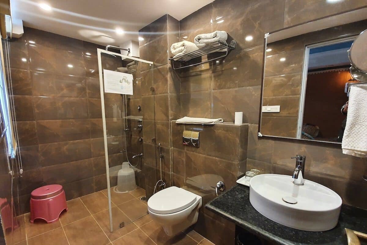 A modern bathroom with a glass-enclosed shower, a white toilet, and a sink with a mirror above it.