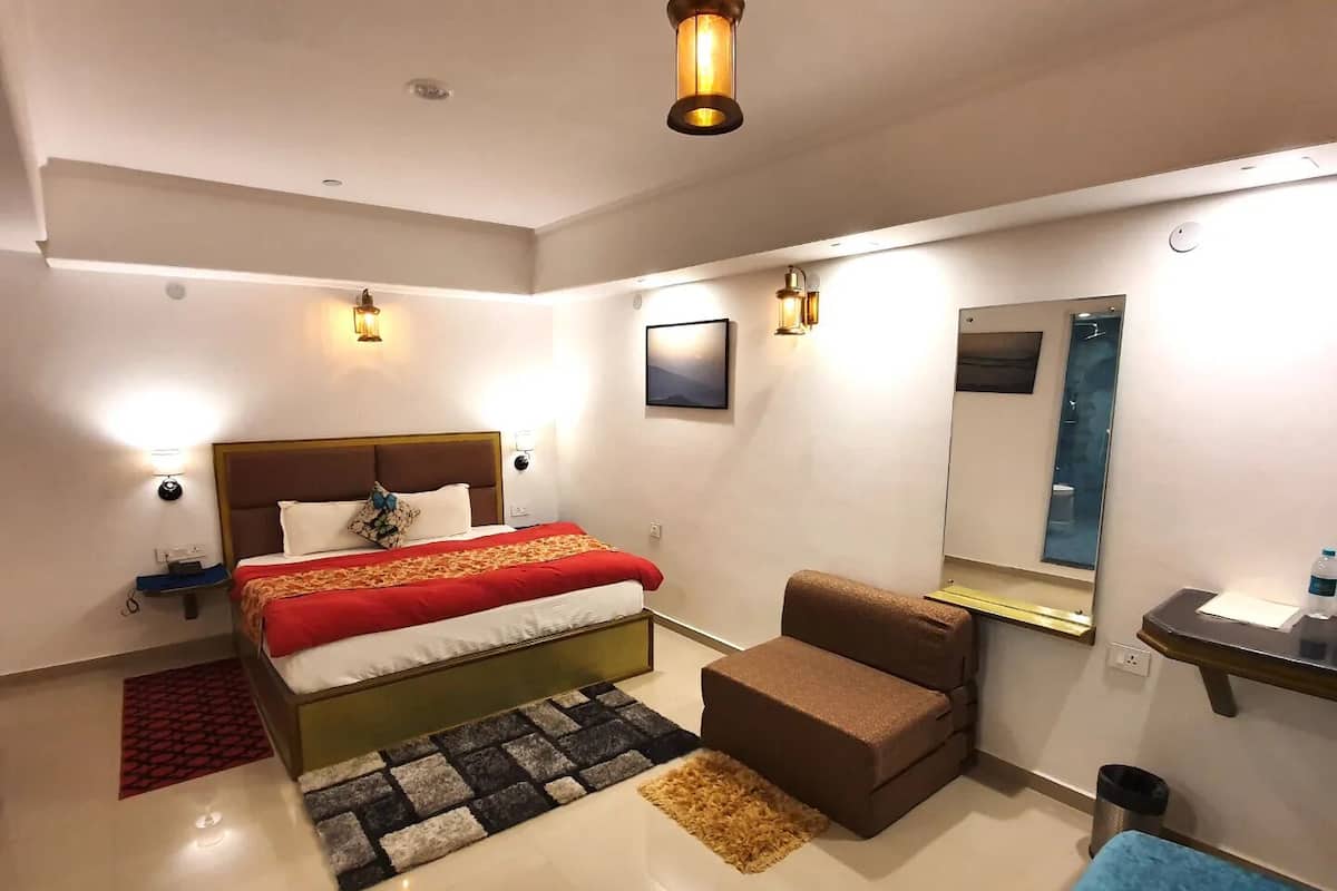 A modern bedroom with a bed, a small seating area, a mirror, and a nightstand.