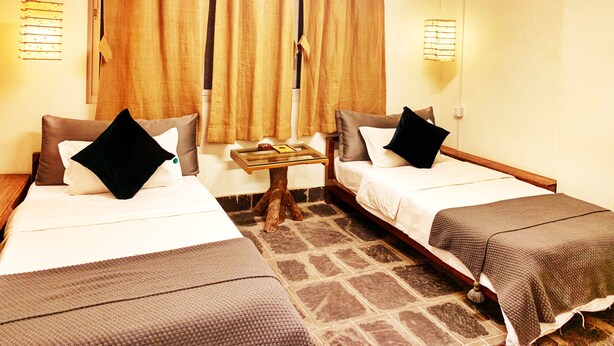 Une chambre d’hôtel avec deux lits, une petite table et une fenêtre avec des rideaux.