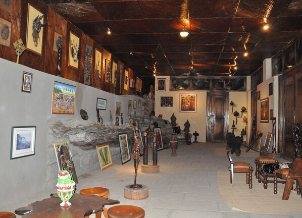 Ein Innenraum mit einer Steinwand, Holzbalkendecke und verschiedenen gerahmten Kunstwerken.