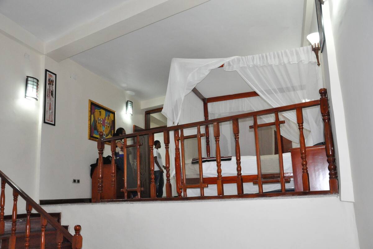 A bedroom with a wooden bed frame, a canopy, and a nightstand.