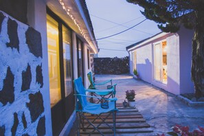 Un étroit sentier mène à un bâtiment doté d’un mur en pierre et d’une terrasse en bois.