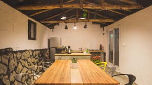 A rustic dining area with a wooden table, metal chairs, and a stone wall.