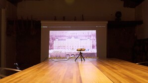 A wooden table with a projector displaying a building image.