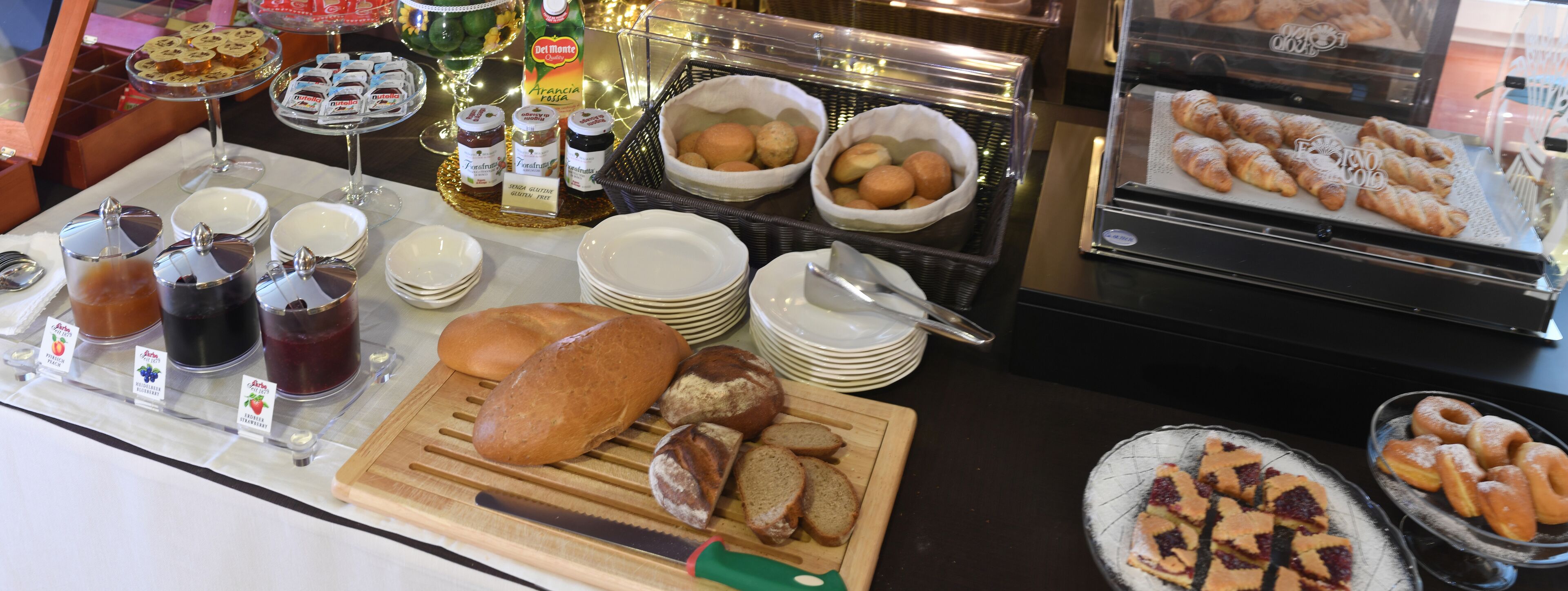 Un buffet de petit-déjeuner proposant un assortiment de pains, de viennoiseries et de condiments.