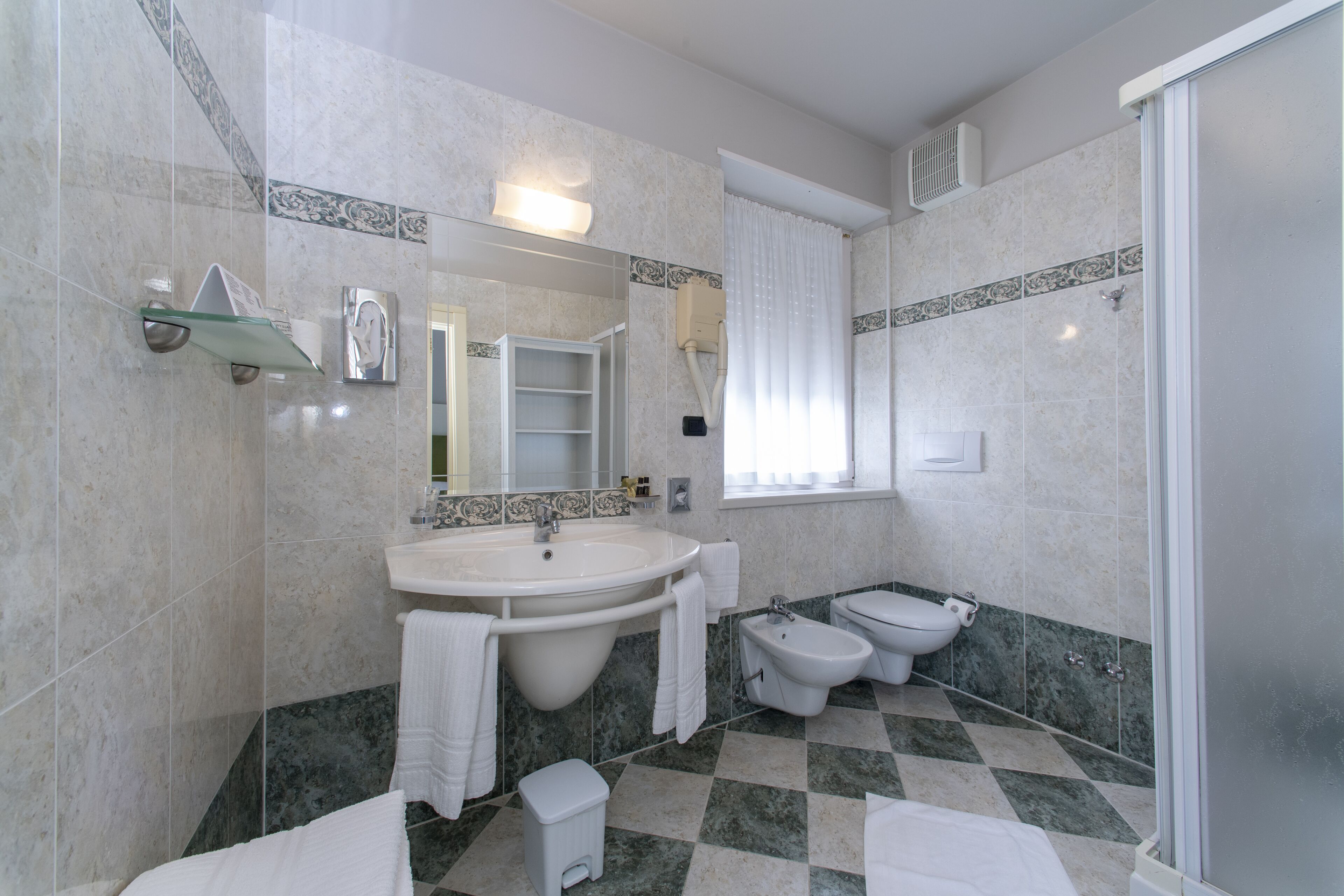 A bathroom with a sink, bidet, toilet, and shower.