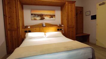 Un dormitorio con estructura de madera, una cama, una mesita de noche, un banco y un cuadro en la pared.