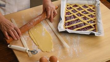 A wooden table with a rolling pin, a dough scraper, and two eggs on a flour-dusted surface.