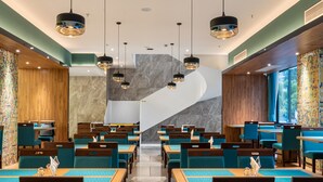A modern restaurant with a central staircase, blue upholstered chairs, and pendant lighting. - Huangshan Tiandu International Hotel (Huangshan)
