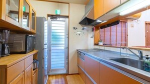 Una cocina compacta con muebles de madera, un lavamanos de acero inoxidable y un microondas.