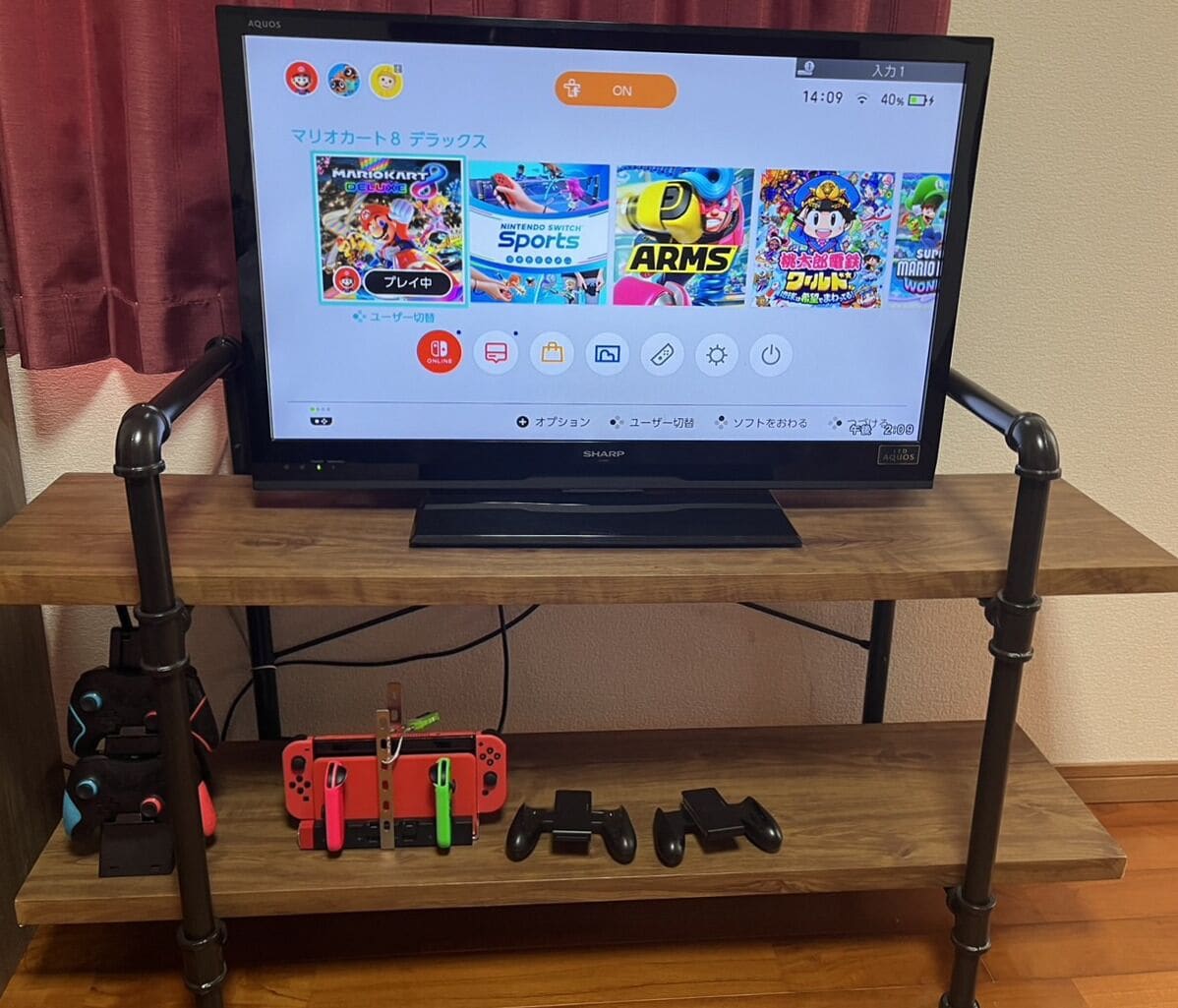 A television on a wooden stand with gaming controllers and a headset.