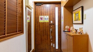 A wooden door with two signs, a reception desk with plush toys, and a framed picture on the wall. - Private Vacation Home COZY (Nago)