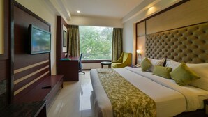 A hotel room with a large bed, a TV mounted on the wall, a desk, and a window with curtains. - Hotel Mint Oodles (New Delhi)