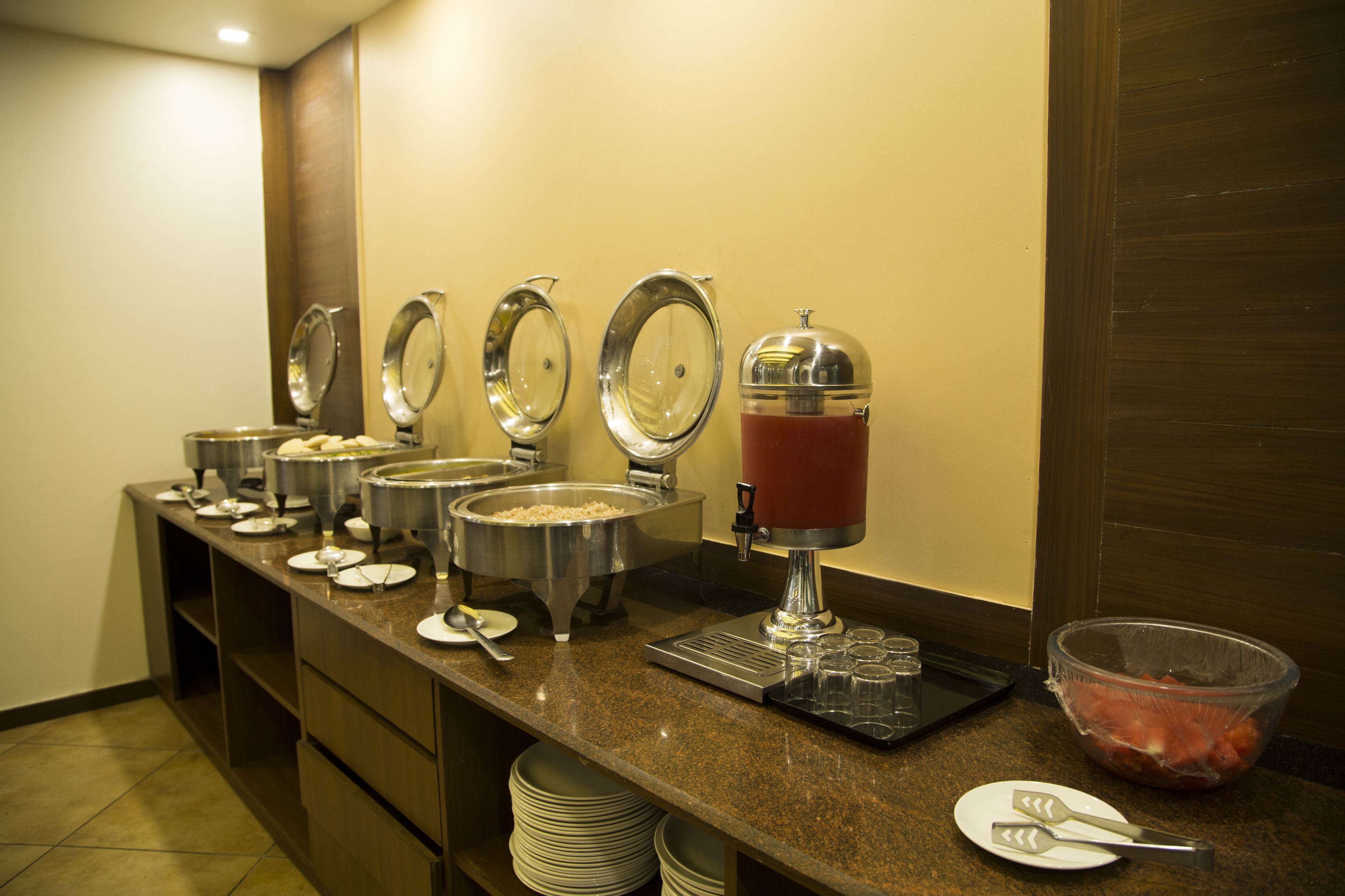 A buffet setup with various food containers and a beverage dispenser.