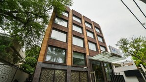 A modern building with a glass entrance, a covered walkway, and a metal gate. - Hotel Mint Oodles (New Delhi)