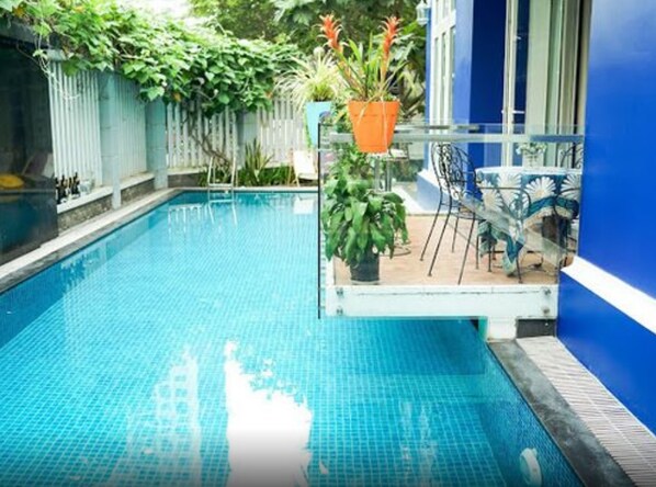 Una piscina con agua azul cristalina, rodeada por un muro azul y una valla de madera.