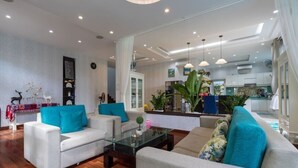A spacious living area with two sofas, a coffee table, and a kitchen in the background. - 5 Bedrooms Pool Villa w Karaoke (Ho Chi Minh City)