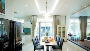 A modern dining area with a long table, chairs, and a chandelier. - 5 Bedrooms Pool Villa w Karaoke (Ho Chi Minh City)
