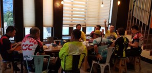 A group of people seated around a table in a restaurant with large windows and a view of the outside.