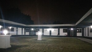 Un edificio con patio interior iluminado de noche, que presenta un pilar blanco central y numerosas ventanas.