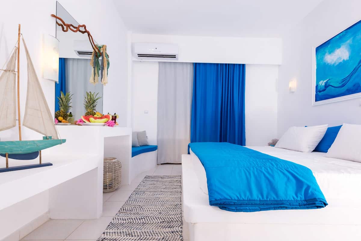 Une chambre d’hôtel moderne, équipée d’un lit, d’un bureau et décorée avec un modèle de voilier.