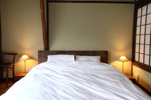A neatly made bed with white linens, two bedside lamps, and a wooden headboard. - HANARé Kyoto (Kyoto)