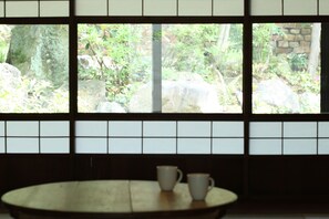 A traditional Japanese room with tatami flooring, a low table with two white cups, and a view of a garden through a shoji screen. - HANARé Kyoto (Kyoto)