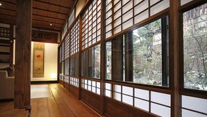 Un interior japonés tradicional con suelo de madera, puertas correderas y vistas a un jardín.